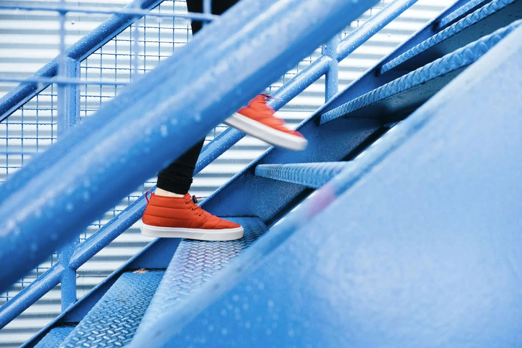 Un pied en chaussure de sport gravit une volée de marches métalliques